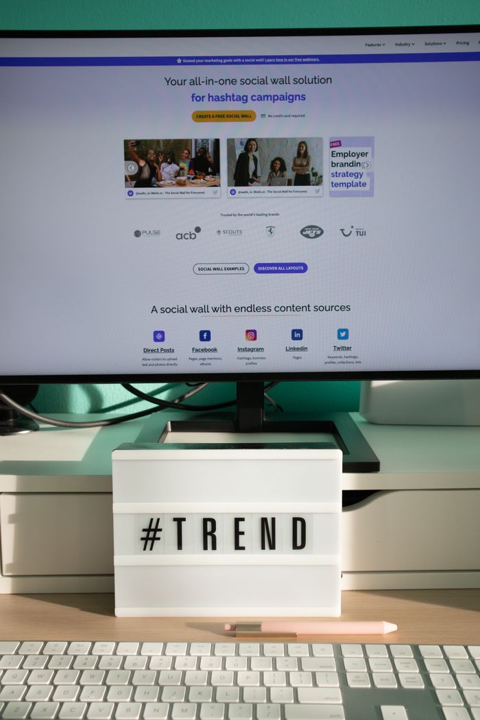 Un espace de bureau épuré et contemporain avec une lightbox affichant #TREND et un écran d’ordinateur présentant une solution de social wall.